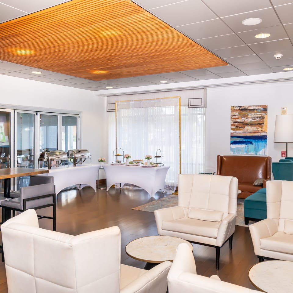 Modern restaurant interior with buffet tables, lounge seating, and a wooden slatted ceiling.